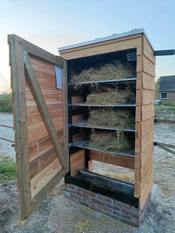 Haybutler DIY (zelfbouw hooivoerautomaat) met houten planken en bakstenen sokkel en open deur